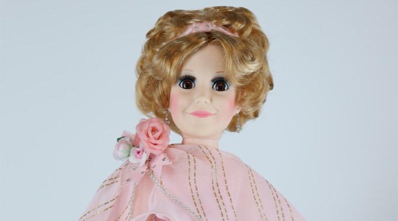 Photo of a doll with a pink dress on. 