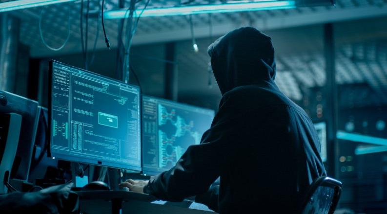 黑客从他的地下藏身处侵入公司数据服务器. 这个地方气氛阴暗，有多个显示器，到处都是电缆.
