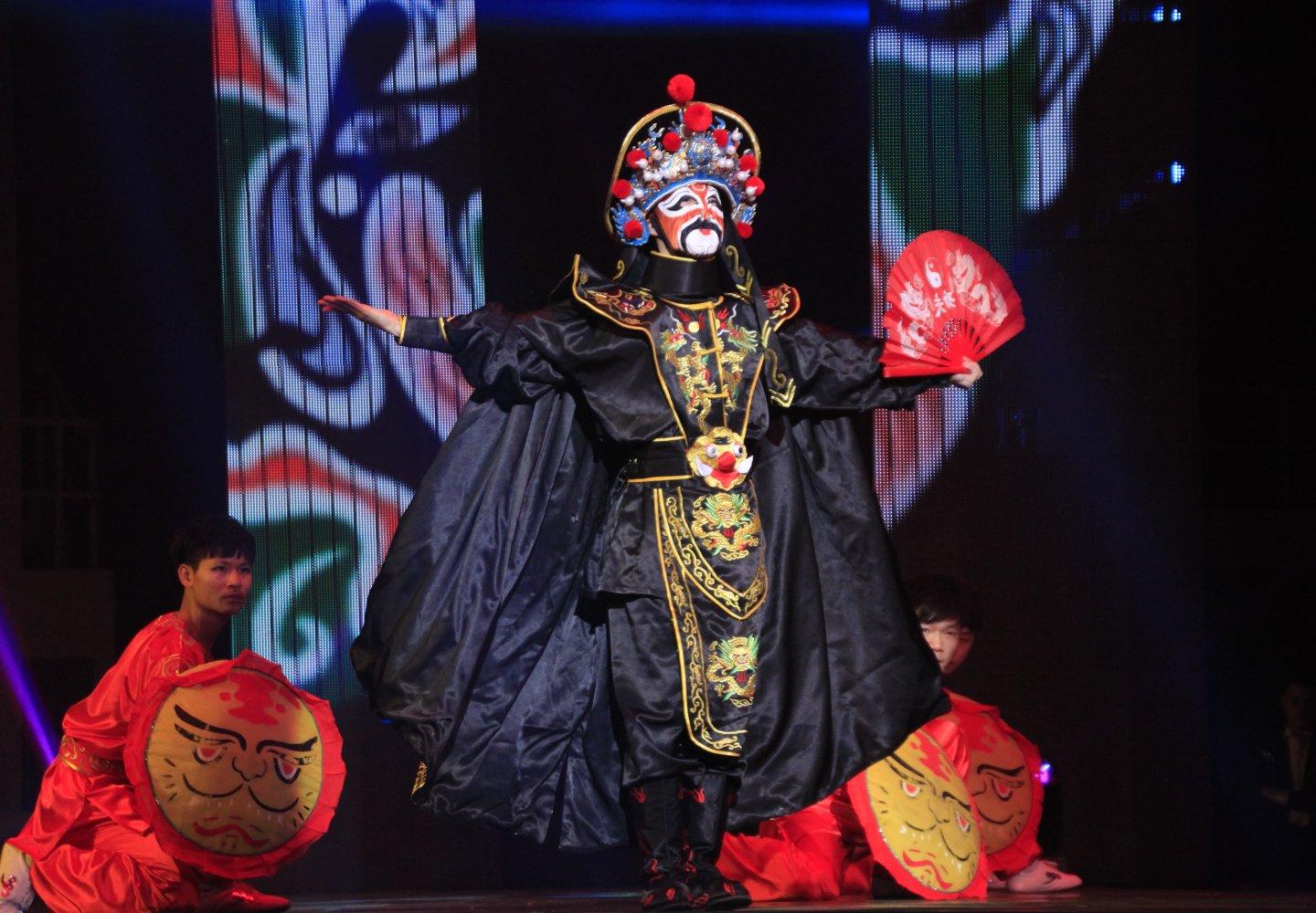 Three performers wear traditional asian attire on stage during theater performance