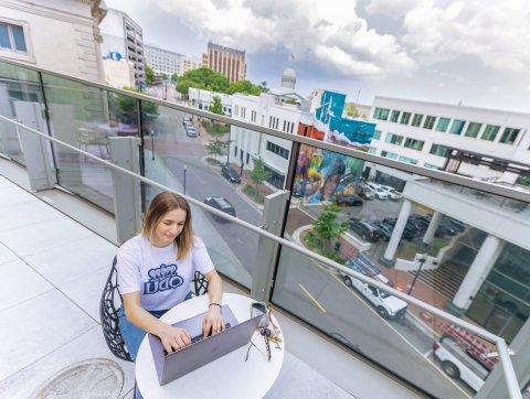 一位金发女学生穿着白色的odu t恤，坐在市中心的屋顶上学习